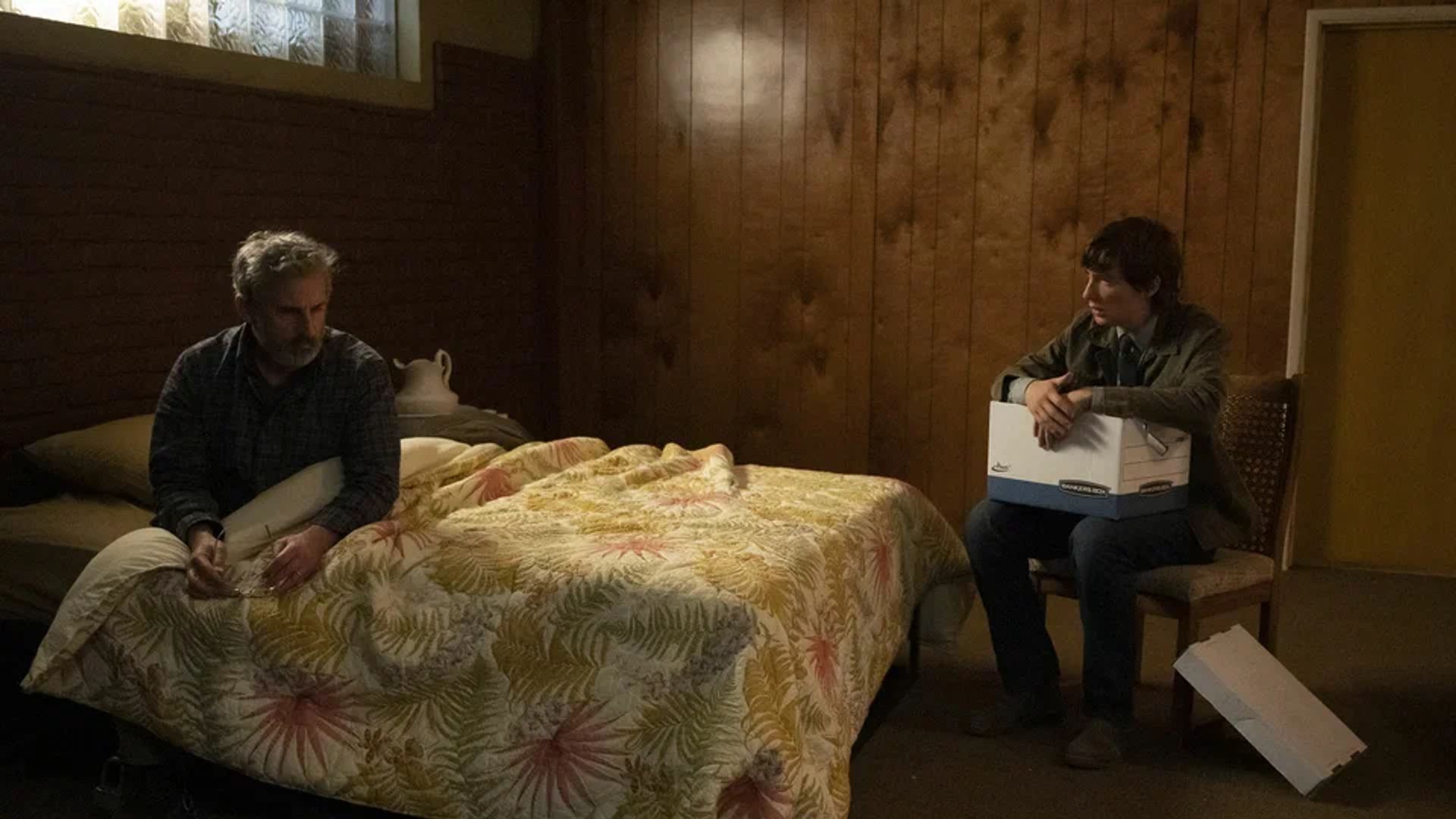 Steve Carell deitado numa cama com Domhnall Gleeson sentado numa cadeira em frente a ele